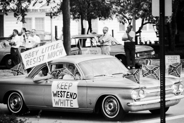 September 1963, Birmingham, Alabama, USA --- Teenagers wave signs and confederate flags from their car during the fight over desegregating Birmingham's public schools. --- Image by © Flip Schulke/CORBIS